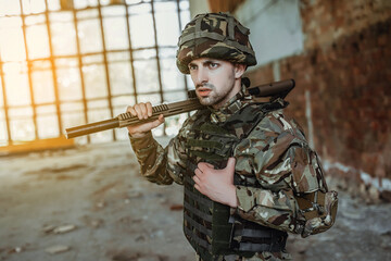 Strong soldier in uniform wears a big rifle in his hands.