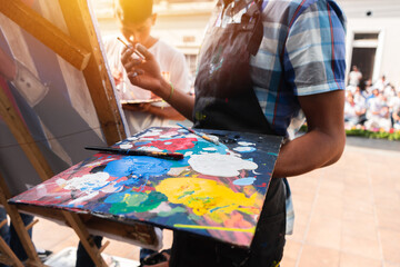 Obraz na płótnie Canvas Young Latinos paint a work of art outdoors