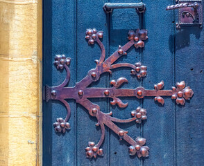 Decorative metal hinge on wooden entrance door.