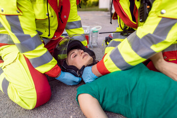 Paramedics removing helmet of injured motorcyclist woman after an accident