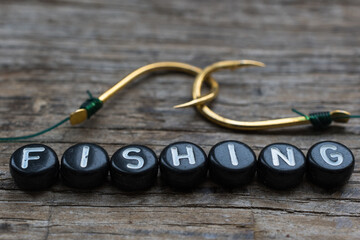 Fishing hooks and text close up on a wooden background.	