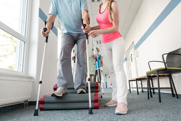 Seniors in rehabilitation learning how to walk with crutches after having had an injury