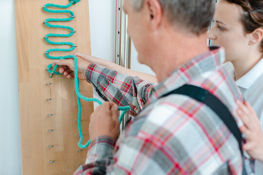 Man in occupational therapy with therapist training his dexterity at the rope board