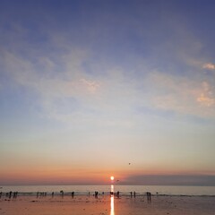 sunset on the beach, blue sky, small clouds