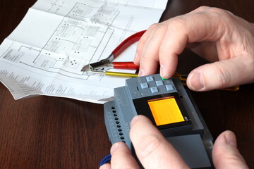 Close-up of a hand setting up a mini PLC.  Testing and programming of an industrial control system.