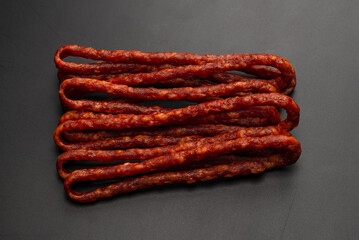 Cabanossi, dry sausage isolated on black background.