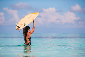 Fototapeta na wymiar Beautiful surfer woman ready to surfing in turquoise sea, on stand up paddle board at exotic vacation