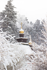Small Orthodox chapel with golden domes is hidden among the snow-covered trees
