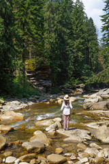 Woman - hiker near  mountain river in forest. Carpathians. Ukraine.