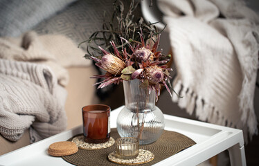 Home composition with a bouquet of protea flowers and candles.