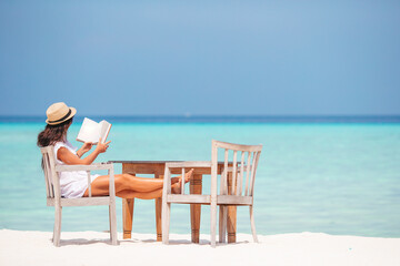 Fototapeta na wymiar Young woman reading book during tropical white beach
