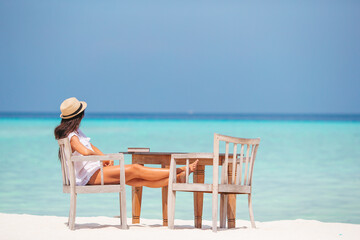 Fototapeta na wymiar Young woman reading at outdoor beach cafe