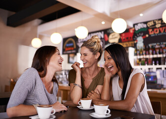 Catching up on the news. Shot of three friends having fun at a coffee shop together.