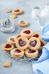 Traditional Linzer cookie with strawberry jam and powder sugar on light grey beautiful background. Top view. Traditional homemade Austrian sweet dessert food on Valentines Day. Holiday snack concept.