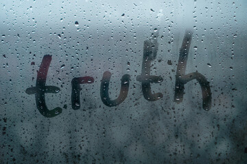 Word TRUTH is written on wet fogged glass on a rainy day