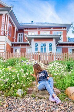 Little blonde girl pick flowers in a meadow full of chamomiles
