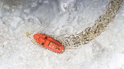 Aerial top down view to the pilot vessel, waiting for cargo ship in the middle of ice covered sea bay