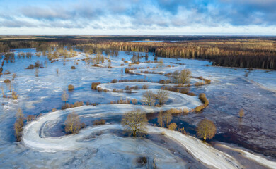 Aerial view to the sunrise colored floodplain with the frozen floodwater and river bends covered with old ice in Soomaa NP, Estonia