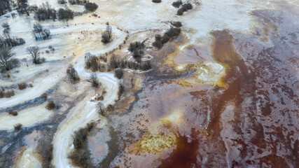 Aerial view to the sunrise colored floodplain with the frozen floodwater and river bends covered...