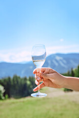hand with glass of sparkling wine on mountains background