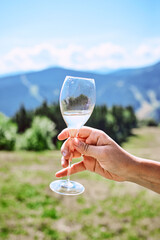 Fototapeta premium hand with glass of sparkling wine on mountains background