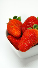 Fresas en recipiente forma de corazón sobre fondo blanco