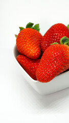 Fresas en recipiente forma de corazón sobre fondo blanco