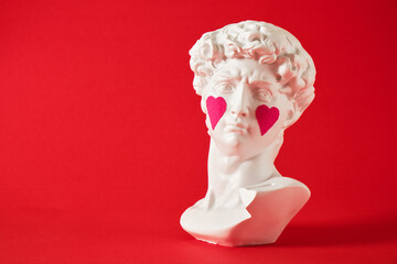 copy of head of antique statue of David with pasted pink hearts on his cheeks, a bright red background,