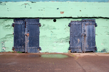 two old black rusty metal door at a concrete wall