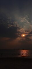 Hidden sun in dark cloud over sea