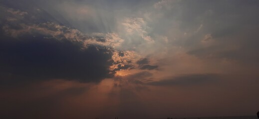Hidden sun in dark cloud over sea