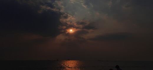 Hidden sun in dark cloud over sea