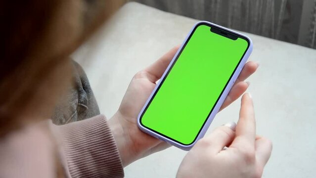a girl flips through a social media feed on a phone with a green screen