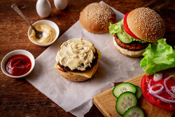 Ingredients for hamburger, cheeseburger. Wooden background. The hamburger is smeared with sauce. Cooking. Hamburger day.
