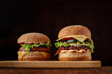 Two hamburgers on a wooden background. Big and small cheeseburger. Hamburger day.