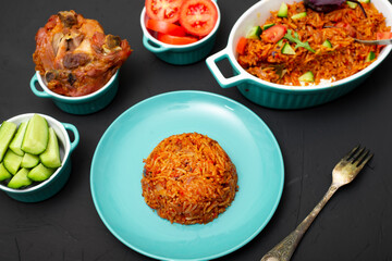 Jollof rice on a plate. Rice with tomatoes, onions, spices. Traditional national Nigerian food. Dark background.