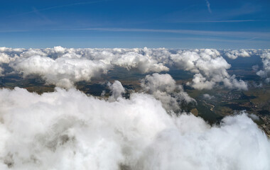 Obraz premium Aerial view from airplane window at high altitude of earth covered with white puffy cumulus clouds