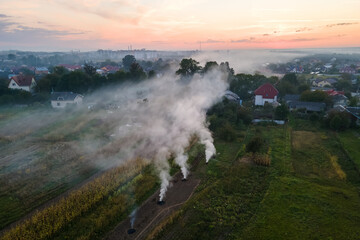 Fototapeta premium Aerial view of agricultural waste bonfires from dry grass and straw stubble burning with thick smoke polluting air during dry season on farmlands causing global warming and carcinogen fumes