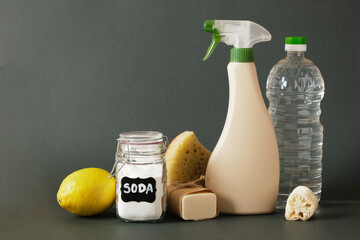 spray bottle, soap, luffa, soda jar, lemon, wooden brush and sponge on hb dark green background copy space - Powered by Adobe