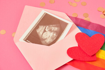 red felt heart and flag rainbow of colors and pregnancy ultrasound scan in pink envelope, pregnancy and lgbt