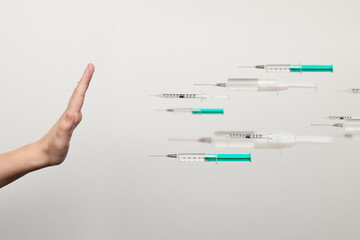 A human hand stopping a flock of syringes in front of her. The problem of anti-vaccination