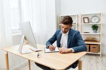 businessmen writes in documents at the desk in the office Gray background