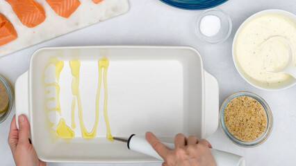 Chef pouring olive oil into baking dish. Baked salmon, and vegetable casserole recipe, step by step...