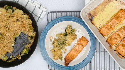 Baked salmon and baked cauliflower and broccoli casserole close up on kitchen table, flat lay