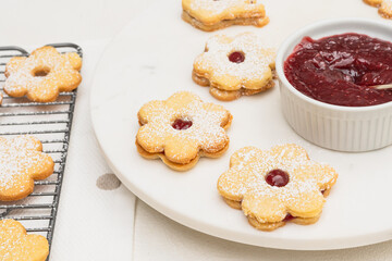 Flower shaped shortbread cookies filled with raspberry jam close up on white background