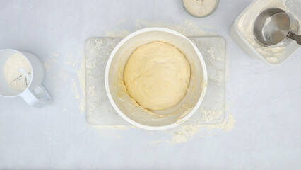 Obraz na płótnie Canvas Raised bread dough in a bowl, view from above. Step by step cheese bread recipe, baking process