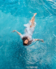 beautiful young sexy woman with vitiligo disease swimming in wet white dress in turquoise water of...