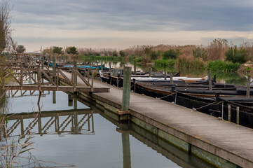 barcos de madera amarrados a los muelles y pasarelas de madera, en el puerto de Catarroja ,en la albufera de valencia ,con un cielo nublado .