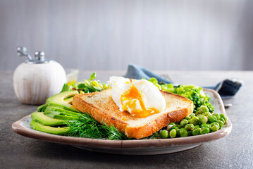 Whole wheat toasted bread with avocado, poached egg, pea on plate. Top view. Healthy diet breakfast