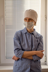 Fototapeta na wymiar A female doctor stands in the hospital wearing a blue uniform and a face mask.